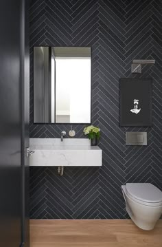 the bathroom is decorated in blue and white with herringbone tile on the walls, along with a toilet and sink