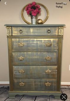 an old dresser with gold paint and flowers on top