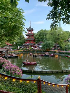 a pond with boats in it surrounded by trees and flowers on either side of the water