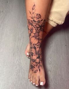 a woman's foot with flowers on it and a tattoo design on the side