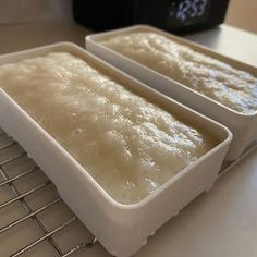 two pans filled with batter sitting on top of a counter next to a cooling rack