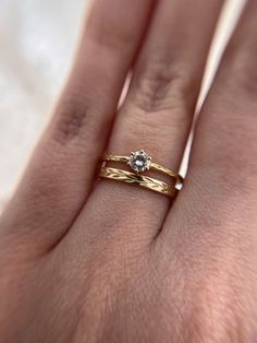 a woman's hand with two gold rings on it and a diamond in the middle