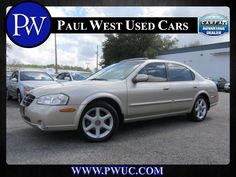 a silver car parked in a parking lot with other cars behind it and an advertisement for paul west used cars