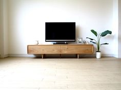 a flat screen tv sitting on top of a wooden entertainment center next to a potted plant