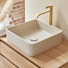 a white sink sitting on top of a wooden counter next to a faucet