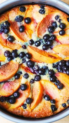 a pie with blueberries and peaches on it is sitting on a wooden table