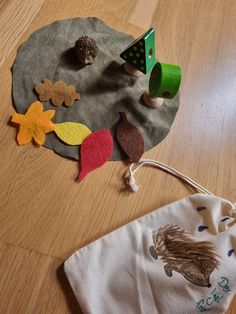 a bag with felt leaves and trees on it next to a drawstring bag