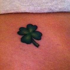 a four leaf clover tattoo on the back of a woman's stomach is shown