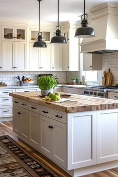 a kitchen with white cabinets and wooden counter tops, an island in the middle is surrounded by hanging lights