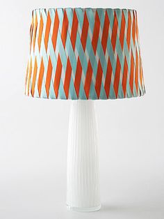 an orange and blue lampshade on a white table with a lamp shade over it