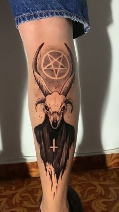 a person with a goat head and pentagramil tattoo on their leg, standing in front of a wall