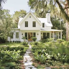 a white house surrounded by trees and plants