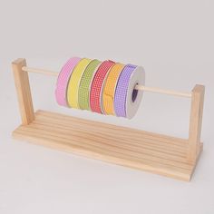 a wooden stand with several rolls of colored tape on top of each other and one roll in the middle