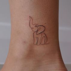 an elephant tattoo on the side of a woman's ankle is shown in black ink