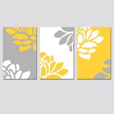 three yellow and gray wall art prints with flowers on the bottom, one in grey and white