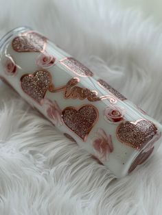 a pink and white canister with hearts on it sitting on a fluffy white surface