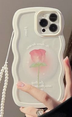 a woman holding up a phone case with a pink rose on it