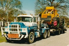 a tractor trailer hauling a large truck down a street