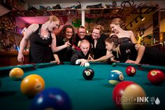 a group of people standing around a pool table