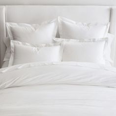 a bed with white sheets and pillows on it