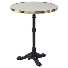 a small round table with an iron base and gold leaf decoration on the top, against a white background