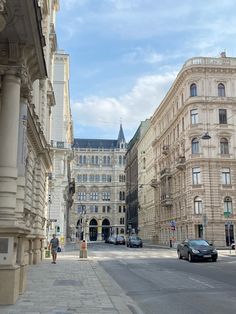 cars are parked on the side of an empty street in front of large buildings with tall spires