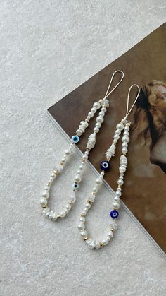 three necklaces are laying on the floor next to a book with an image of a woman