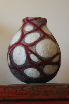 a white and red vase sitting on top of a wooden table