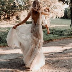 a woman walking down a dirt road wearing a dress