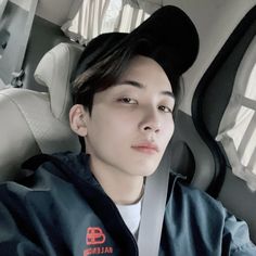 a young man sitting in the back seat of a car wearing a mickey mouse hat