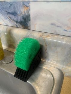 a green brush sitting on top of a metal sink