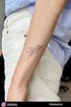 a woman's arm with a small flower tattoo on the left side of her arm