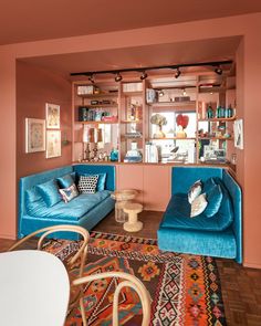 a living room with two blue couches and a rug on the floor in front of a bookshelf