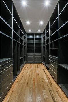 an empty walk - in closet with wooden flooring and black shelving unit units