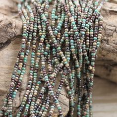 several strands of beads are sitting on a piece of wood