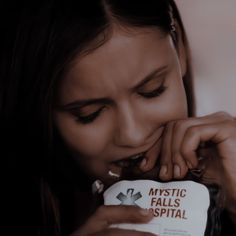 a young woman biting into a package of candy with the words mystic falls hospital on it