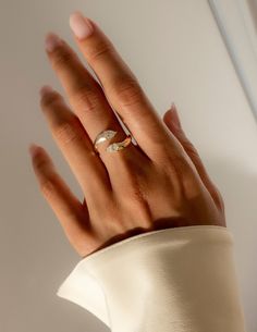 a woman's hand with a gold ring on top of her left hand, wearing a white dress shirt