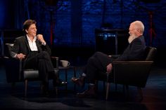 two men sitting in chairs talking to each other