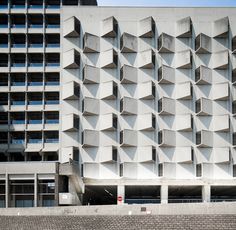 a large building with many windows next to a brick wall on the side of it