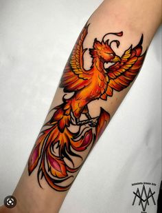 a bird tattoo on the arm with orange and red colors, flying in the air