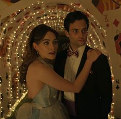 a man in a tuxedo standing next to a woman wearing a dress and bow tie