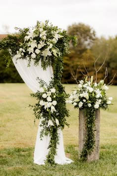 an outdoor ceremony setup with white flowers and greenery