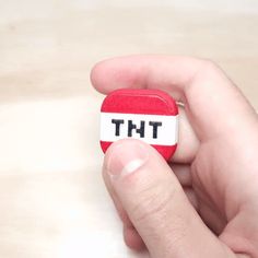 a person holding a small red object with the word tht on it's side