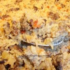 a spoon full of food with meat and rice on it's side in a casserole dish