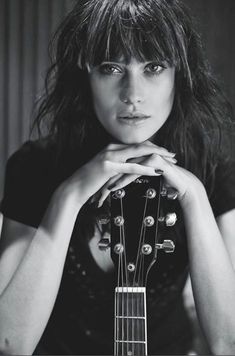 black and white photograph of a woman holding an acoustic guitar in front of her face