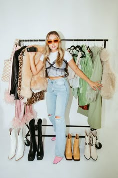 a woman standing in front of a rack with clothes and shoes on it's legs