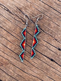 two pairs of beaded earrings sitting on top of a wooden table