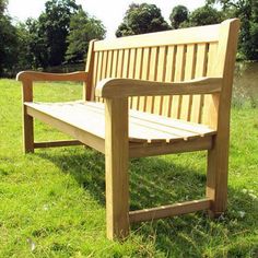 a wooden bench sitting on top of a lush green field with trees in the background