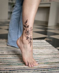 a woman's foot with a rose tattoo on her left leg and the bottom part of her body visible