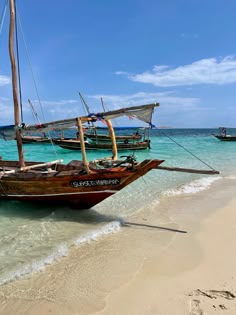 two boats sitting on the beach next to each other in the ocean with clear blue water